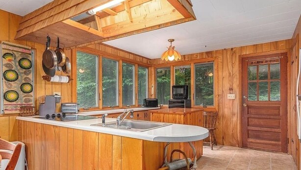 A wooden cabin kitchen with a large island, wooden walls, and large windows. - Charming 2-bedroom cabin in Waynesville (Waynesville)