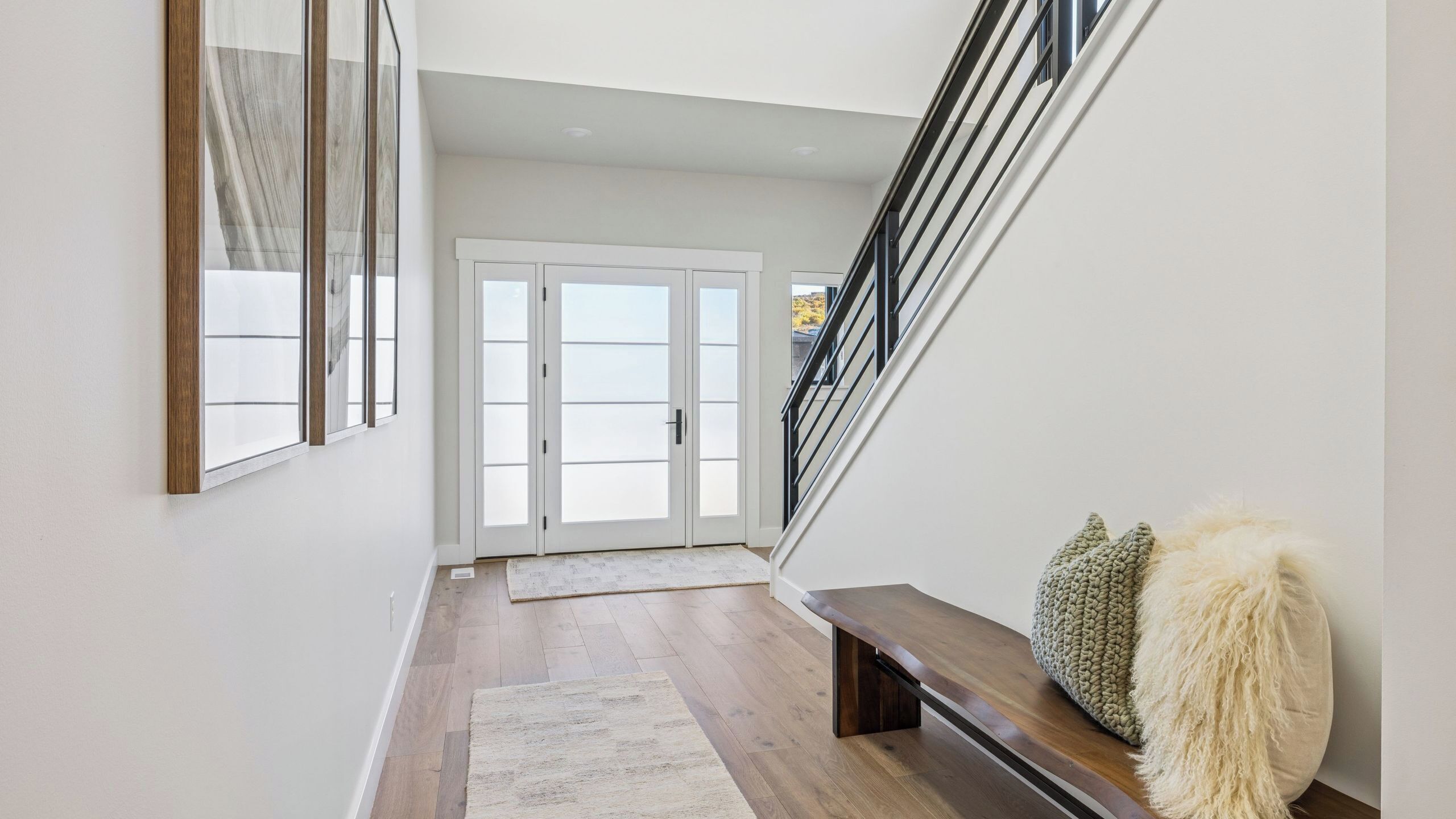 Ein modernes Interieur mit einer Holzbank, einem flauschigen Kissen und einer Treppe.