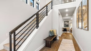 A staircase with a wooden handrail and carpeted steps leading to a second floor. A bench is placed against the wall, and a large framed artwork is visible on the wall. - Hot Tub, BBQ & Mtn Views Near Deer Valley & Park City Deer Valley East Retreat by Avantstay (Heber City)