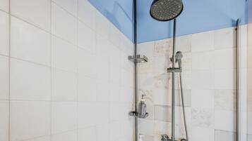 Une douche équipée d’un pommeau de douche à main, d’un robinet mural et d’un distributeur de savon.