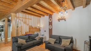 A living room with two sofas, a wooden coffee table, and a fireplace. - El Rinconcito de Cinderellana – Rural House in Sierra de la Demanda (La Revilla)