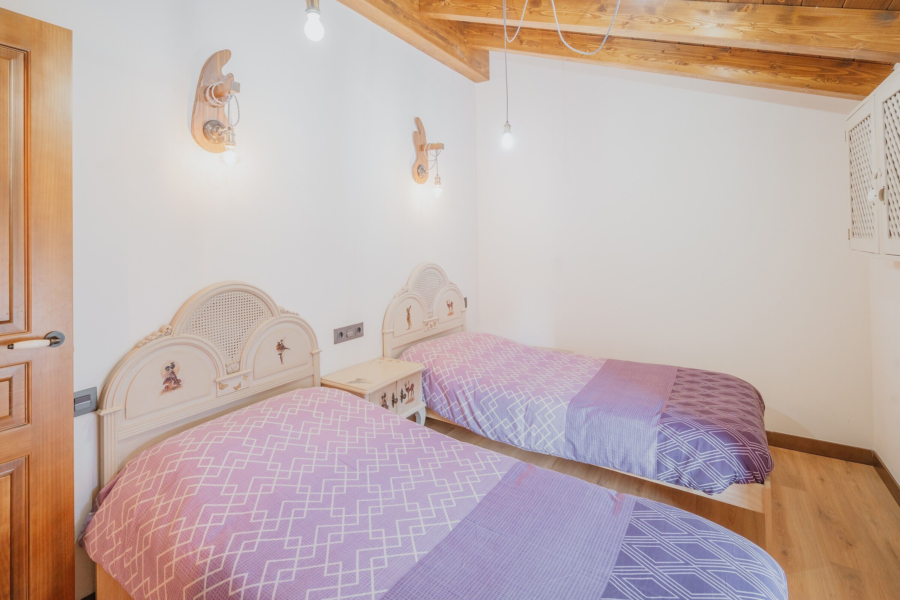 Ein Schlafzimmer mit zwei Betten, Holzkopfteilen und Wandleuchten.