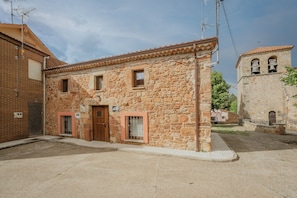 A stone building with a tiled roof, a wooden door, and a small window.