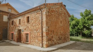 A stone building with a tiled roof, a wooden door, and a window. - El Rinconcito de Cinderellana – Rural House in Sierra de la Demanda (La Revilla)