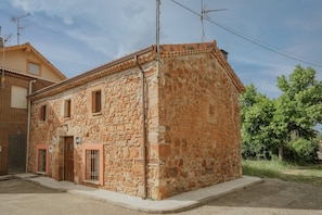 A stone building with a tiled roof, a wooden door, and a window.