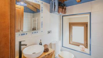 Een badkamer met een houten wastafelmeubel, een witte wastafel, een toilet en een spiegel.