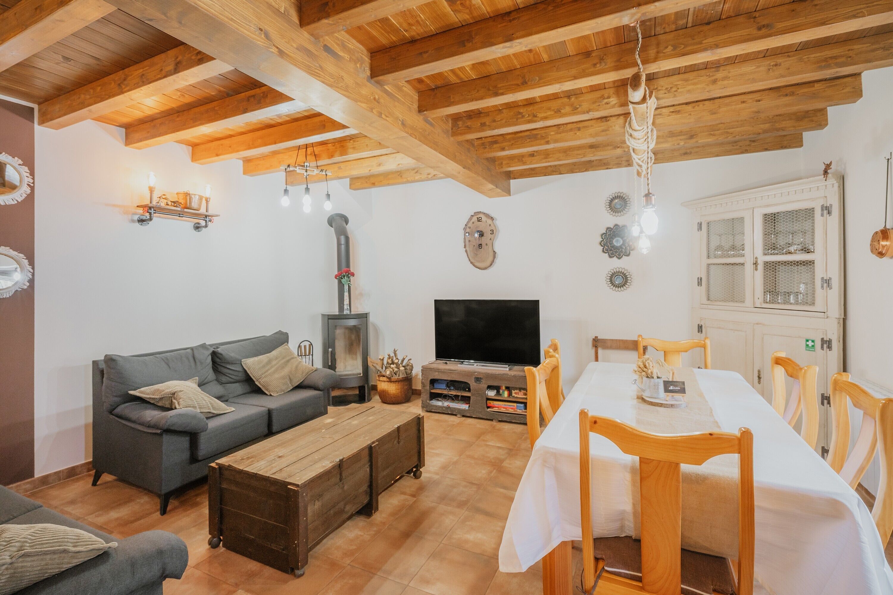 Una sala de estar con sofá, mesa de centro de madera, televisor y comedor con sillas y una mesa.
