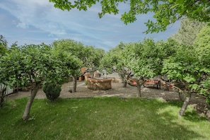 A courtyard with trees, a stone fountain, and a red cart.