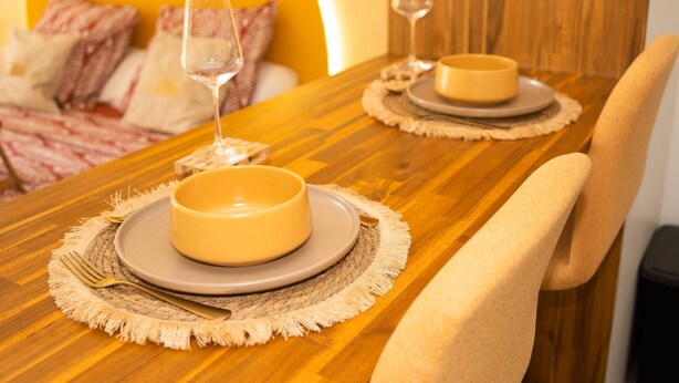 A dining table set with plates, cutlery, and glasses, with a chair positioned at the table. - Cocon Chic  Res de Charme (Cayenne)