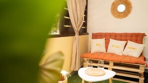 A cozy room with a wooden sofa, a round mirror, and a small table with glasses. - Cocon Chic  Res de Charme (Cayenne)