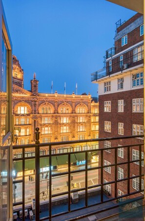 Une vue depuis un balcon donnant sur une rue, avec un bâtiment historique à l’architecture riche et un bâtiment moderne à la façade en briques.