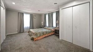 Une chambre à coucher comprenant un lit, une table de chevet, une commode et un placard.