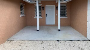 A covered patio area with a door, two windows, and a white pergola structure.