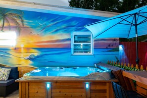 A hot tub with a sunset mural, wooden deck, and a window.