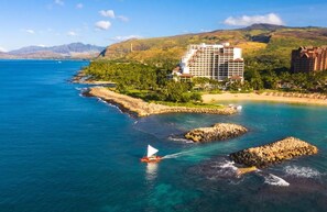 Ein Küstenhotel mit mehreren Gebäuden, einem Strand und Felsenformationen.