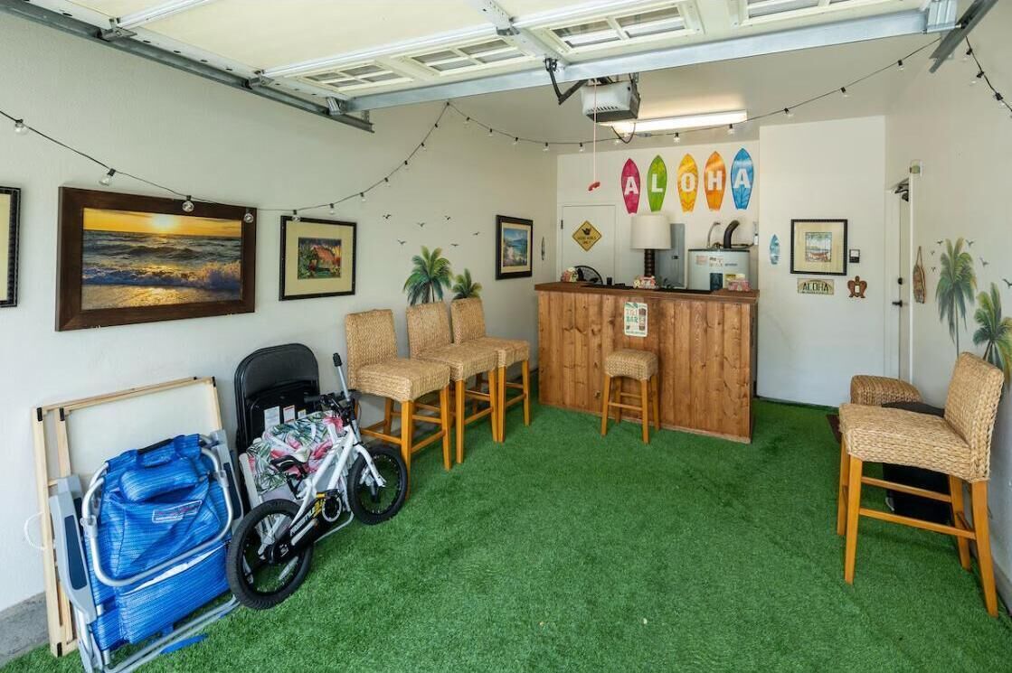 A room with artificial grass, wicker chairs, a wooden desk, and a bicycle.
