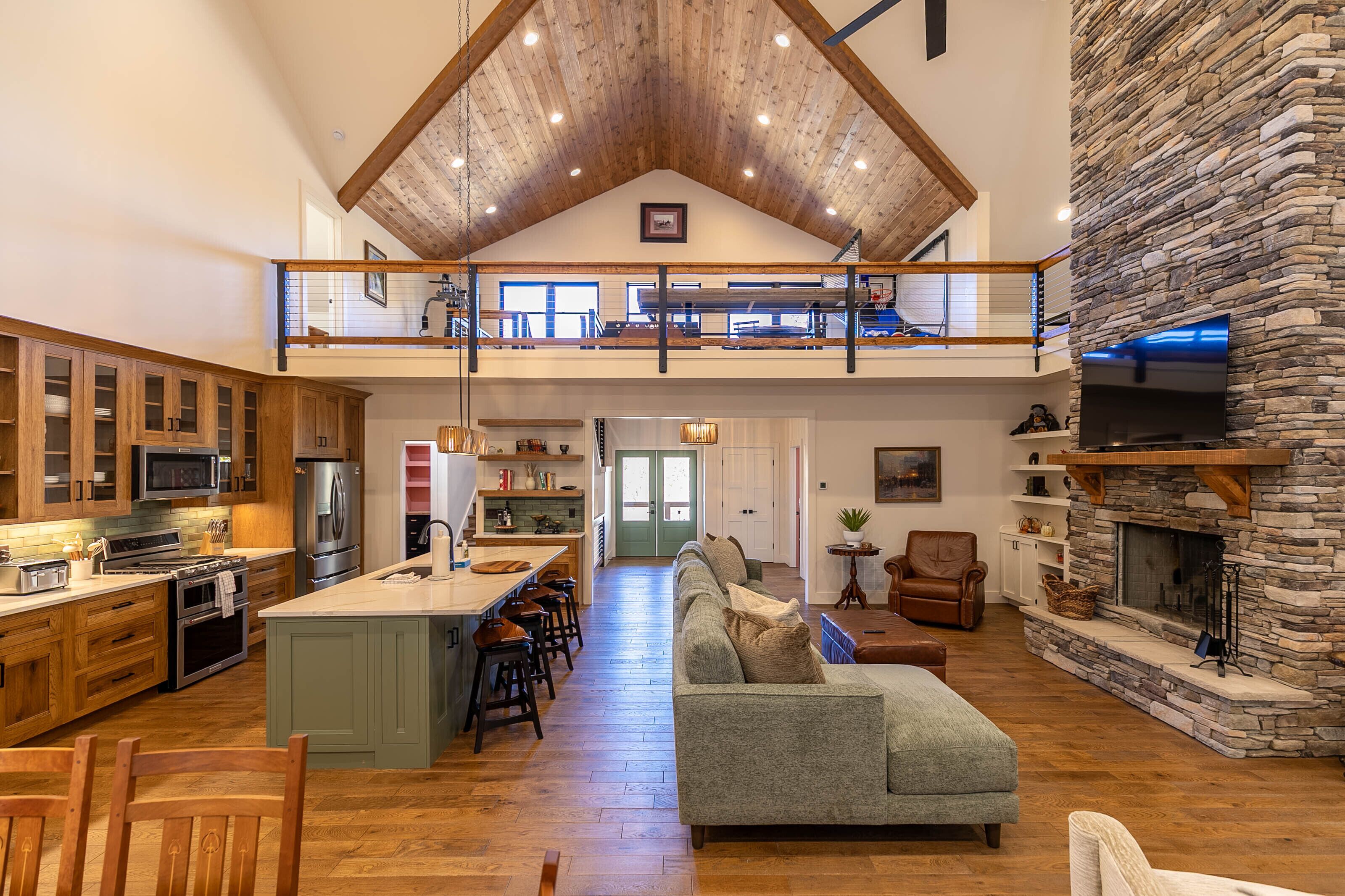 A spacious loft-style living area with a kitchen, dining area, and a stone fireplace.