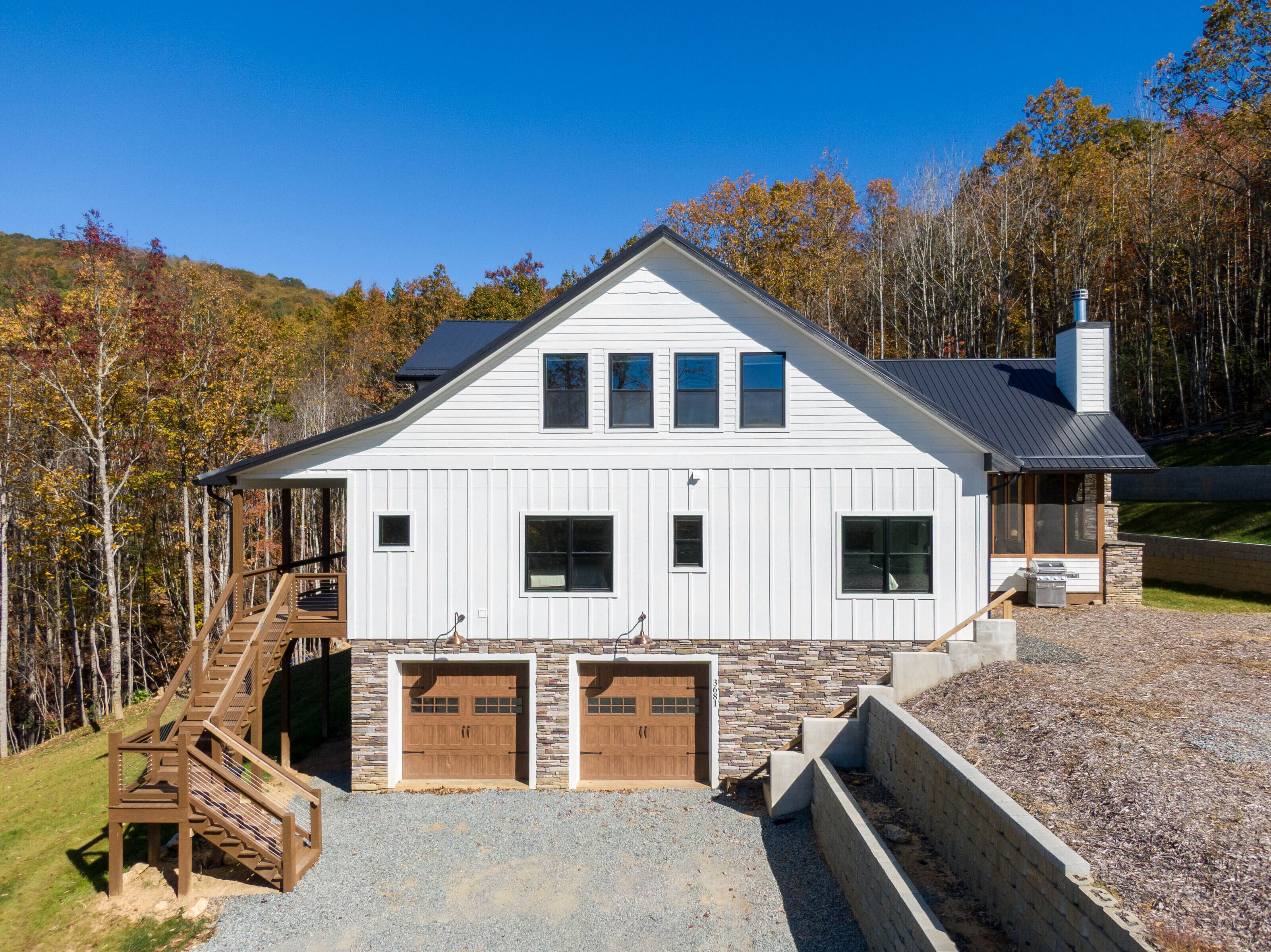 A two-story house with a stone foundation, a wooden deck, and a garage.