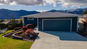 A modern two-story house with a garage, surrounded by a well-maintained garden and a mountain backdrop. - Summerset Poolside Paradise (Manson)