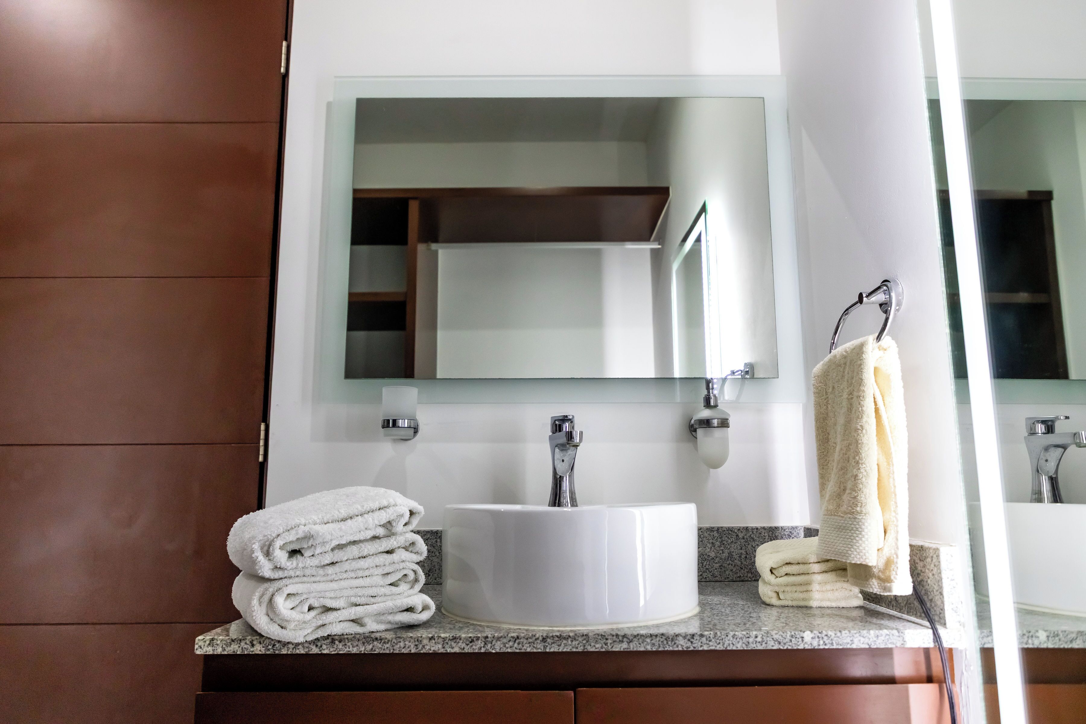 A bathroom with a white sink, a mirror, and a towel rack.