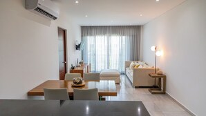 Ein modernes Wohnzimmer mit Essbereich, einer Couch, einem Couchtisch und einer Lampe.