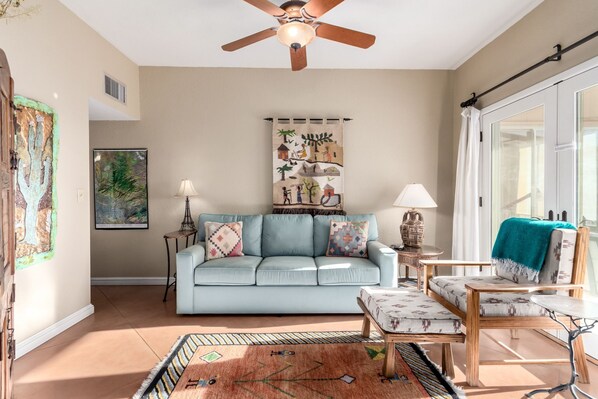 A living room with a light blue sofa, a wooden coffee table, and a patterned rug. - Mountain & Sunset Views (Tucson)