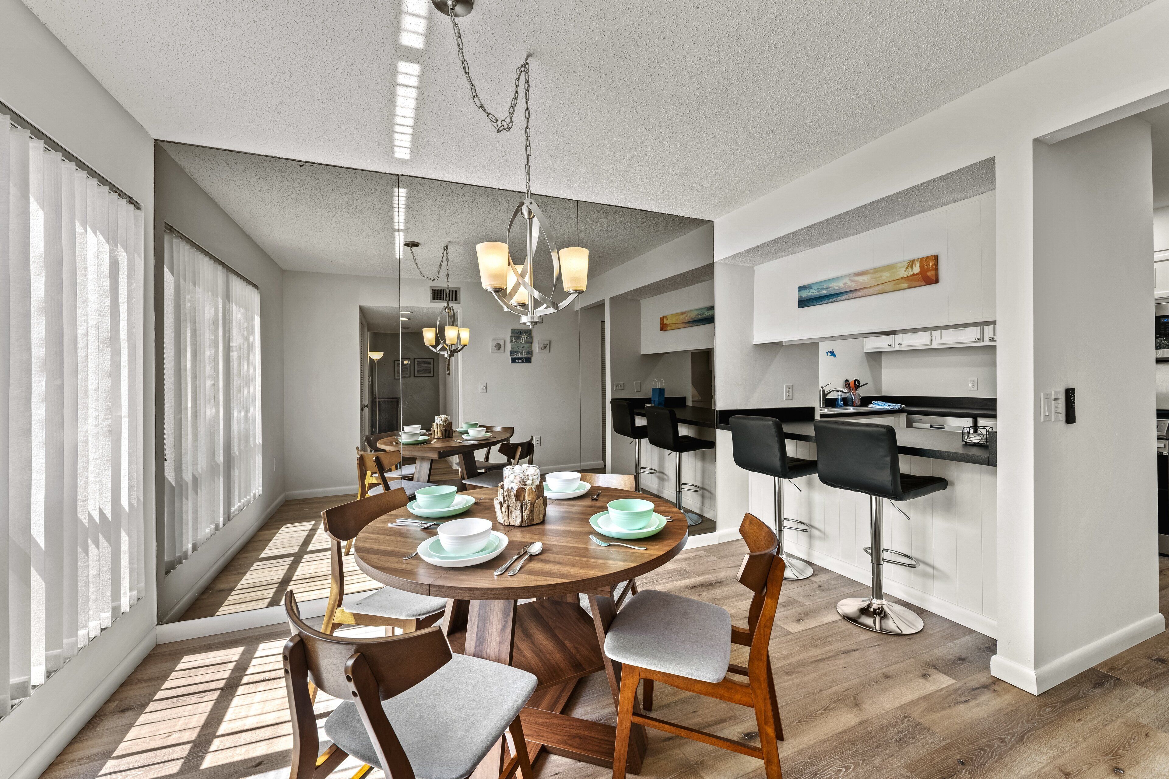 A modern kitchen with white cabinets, a black countertop, and a hanging light fixture.