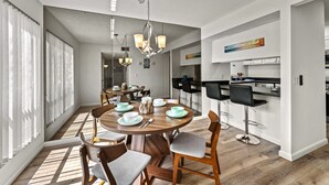 Une cuisine moderne avec des armoires blanches, un comptoir noir et un luminaire suspendu.