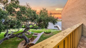 Un balcon donnant sur un parc et un plan d’eau, au coucher du soleil.