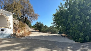 Un sendero pavimentado que conduce a un edificio de piedra con fachada blanca y una ventana pequeña.