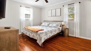 Un dormitorio con cama, ventilador de techo, mesita de noche y televisión.