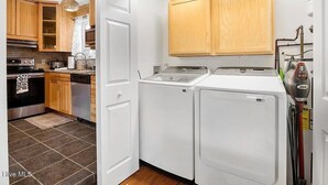 Cocina con armarios de madera, lavavajillas y lavadora.