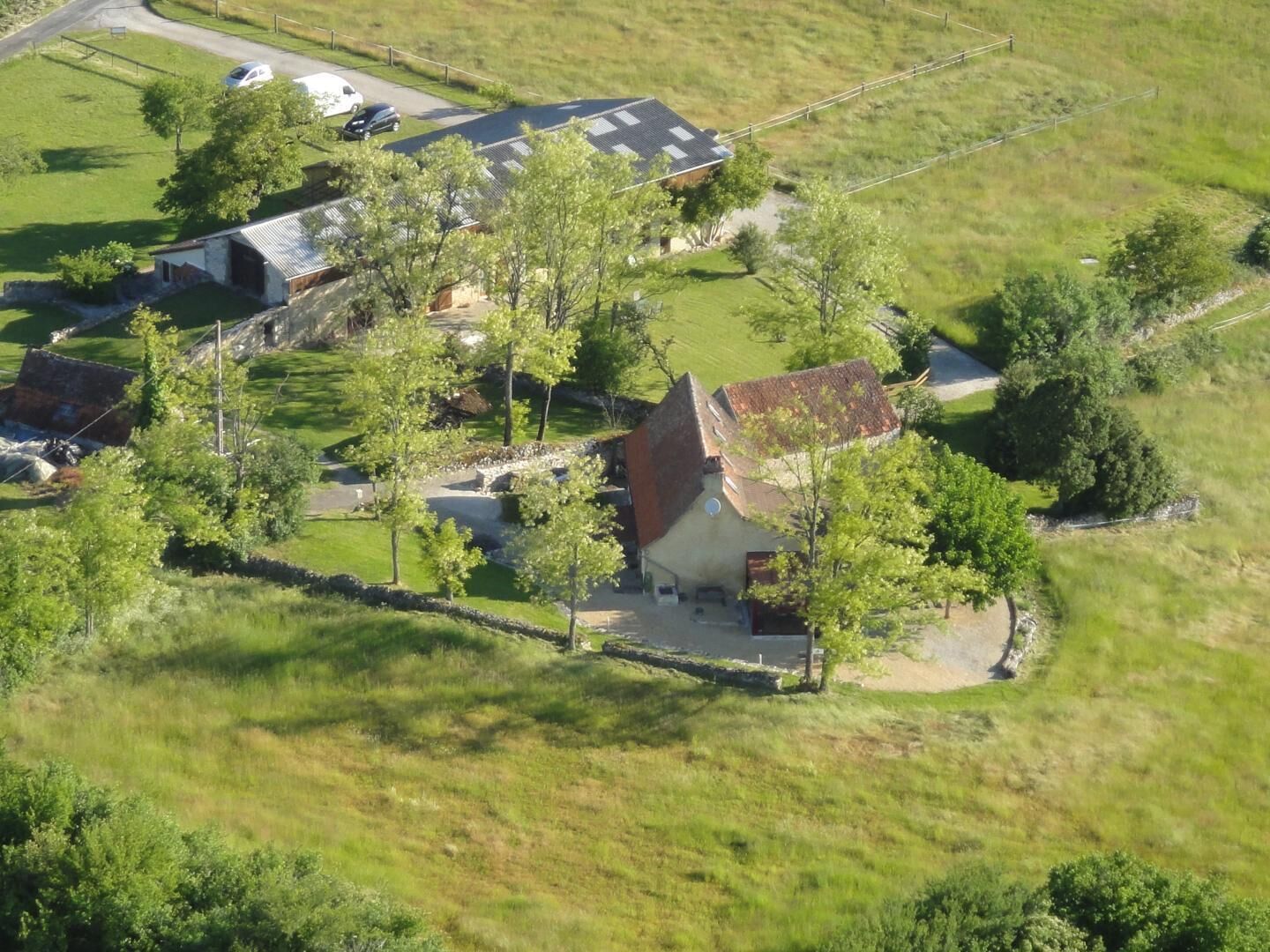 A rural property with multiple buildings, a fenced yard, and a road.