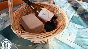 A wicker basket with a bottle and a box on a tiled floor. - Gîtes de France® - Le Fenil (ROCAMADOUR)