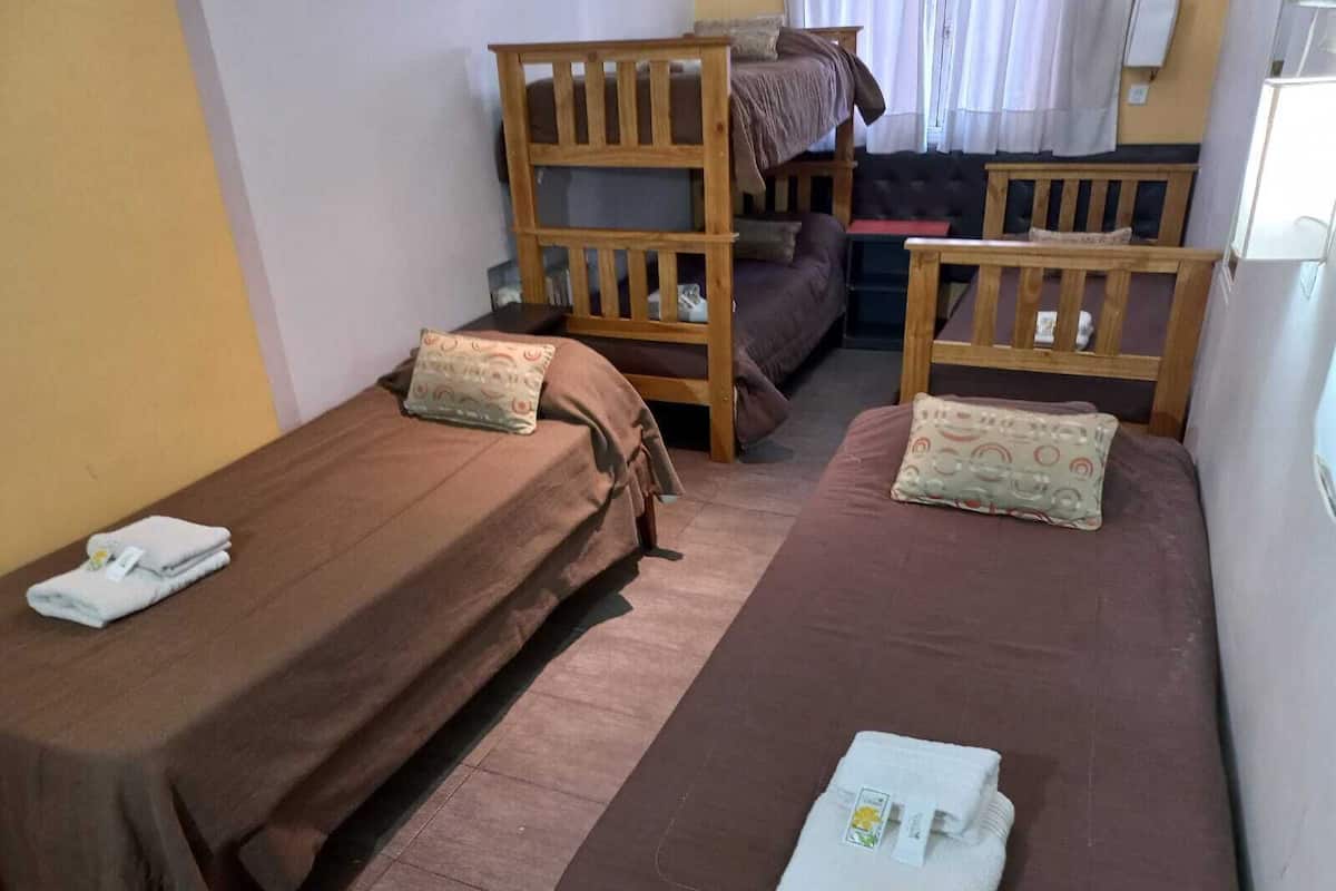 A room with two single beds, a sofa, and a wooden bunk bed.