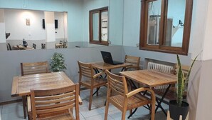A dining area with wooden tables and chairs, a laptop on one table, and a potted plant. - Petit Hotel (Mendoza)