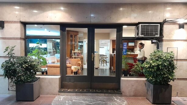 A hotel entrance with a revolving door, potted plants, and a tiled floor. - Petit Hotel (Mendoza)