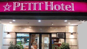 The exterior of the Petit Hotel with a prominent star logo, a glass entrance, and potted plants at the entrance. - Petit Hotel (Mendoza)