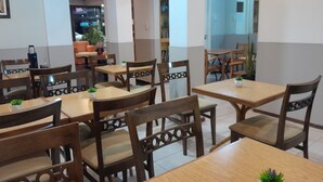A dining area with wooden tables and chairs, some with plants. There are framed pictures on the walls. - Petit Hotel (Mendoza)