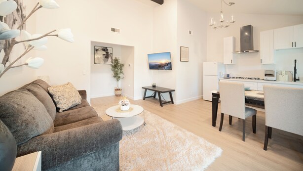 Uma sala de estar moderna com sofá, mesa de centro e área de jantar.