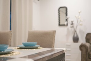A dining table with a blue bowl and plate, a vase with flowers, and a mirror on the wall. - 2 TVs  Vaulted Ceiling  Private Kitchen&Entrance (Walnut)
