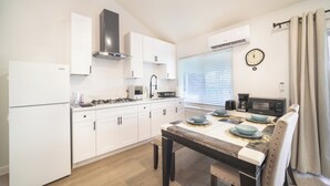 Uma cozinha moderna com armários brancos, uma mesa de jantar com pratos azuis e um relógio na parede.