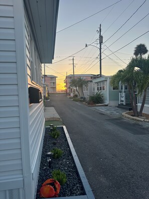 A residential street with houses, a 'For Sale' sign, and a clear sky. - Villa Salt + Sea – Anna Maria Island (Bradenton Beach)