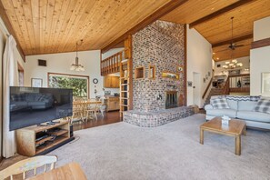 A spacious living area with a fireplace, wooden ceiling, and a television.