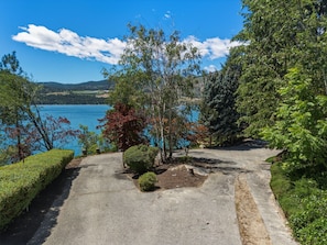 Une allée pavée mène à un belvédère offrant une vue panoramique sur un lac et des collines en arrière-plan.