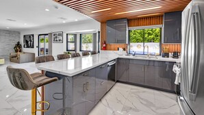 A modern kitchen with a large island, grey cabinets, and stainless steel appliances. - HOUSE OF PRINCE – Luxury 4BR Palm Springs retreat with pool, gym & kids’ room. (Palm Springs)