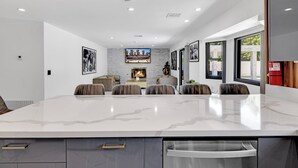 A modern dining area with a large marble table, comfortable seating, a fireplace, and framed artwork on the walls. - HOUSE OF PRINCE – Luxury 4BR Palm Springs retreat with pool, gym & kids’ room. (Palm Springs)