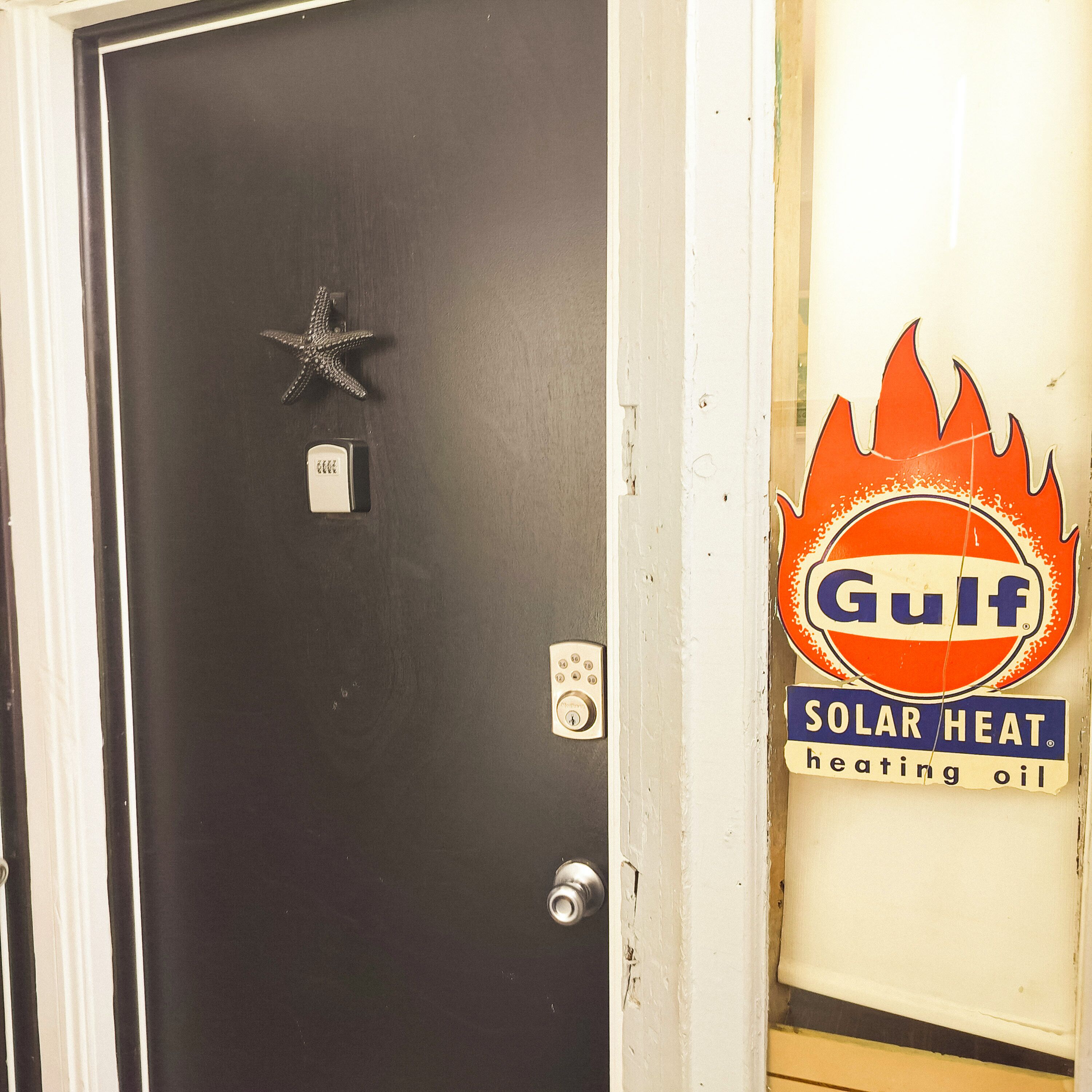 A door with a star-shaped decoration, a keypad lock, and a sign for Gulf Solar Heat heating oil.