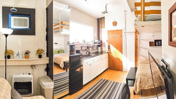 A compact kitchen with a refrigerator, microwave, and sink. There is a small dining area with a bench and a rug. - Cozy Vibe MicroFlat with AC, W/D, FastWiFi in the heart of Fishtown Philadelphia (Philadelphia)