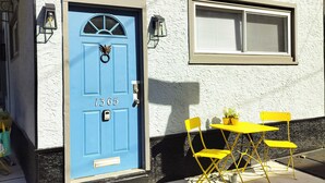 A blue door with the number 1365, a window with blinds, and yellow chairs outside a building with a textured wall. - Cozy Vibe MicroFlat with AC, W/D, FastWiFi in the heart of Fishtown Philadelphia (Philadelphia)